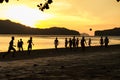 Silhouette group of people playing the football on the beach in the sunset with seascape and mountain in background