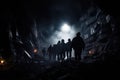 Silhouette of a group of people walking through a dark cave, Silhouette of miners with headlamps entering an underground coal mine