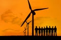 silhouette of group of people with windmills on orange sky background Royalty Free Stock Photo