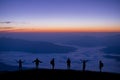 Silhouette group of tourists watch the view of star and milky way and foggy landscape on the top of the mountain and raise their h