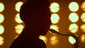 Silhouette guy blowing saxophone on stage closeup. Young saxophonist performing.