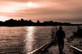 Silhouette of guy in hat fishing in river on sunset