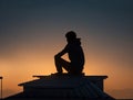 Silhouette of a guy sitting on the roof against the background of a sunset Royalty Free Stock Photo