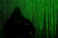 Silhouette of a hacker in a hood with a laptop on a background of a matrix of binary computer code. Concept: hacker and computer Royalty Free Stock Photo