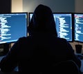 Silhouette of a hacker wearing a hoodie, engaged in coding or hacking on several computer screens