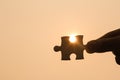 Silhouette of a hand holding a jigsaw puzzle piece with sunset backgroun Royalty Free Stock Photo