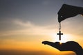 Silhouette of hand holding necklace crucifix background sunrise. Concept for Christian, Christianity, Catholic religion, god