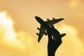 Silhouette of a hand holding a toy plane on a golden sky background Royalty Free Stock Photo