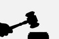 Silhouette of a hand and a judicial hammer on a white background. Judicial practice concept. With place for your text