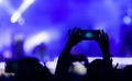 Silhouette hand shoots video on the phone at a rock concert as background