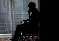 Silhouette of handicapped Man sitting on wheelchair in front of a large panoramic window in hospital