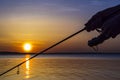 Silhouette of hands of fisherman with fishing spinning rod on sunset background Royalty Free Stock Photo