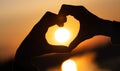 silhouette of hands forming a heart shape with sunset. expression of love and gratitude to the world.