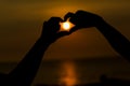 Silhouette of hands making a heart shaped symbol with beautiful sunset background. Royalty Free Stock Photo