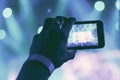 Silhouette of hands with a smartphone at a concert