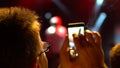 Silhouette of hands using camera phone to take pictures and videos at pop concert