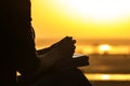 Silhouette of the hands of woman praying to God in the nature witth the Bible at sunset, the concept of religion and spirituality Royalty Free Stock Photo