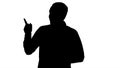 Silhouette Handsome young man walking and looking to the camera and pointing to the sides showing something. Royalty Free Stock Photo