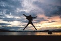 Silhouette happiness man jumping on lake at sunset