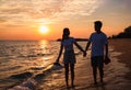 Silhouette of happy Asian couple hands holding and walk together on the beach while golden sunset time evening Royalty Free Stock Photo