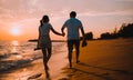 Silhouette of happy Asian couple hands holding and walking together on the beach while golden sunset time evening of summer Royalty Free Stock Photo