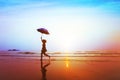 Silhouette of happy carefree girl with umbrella jumping on the beach