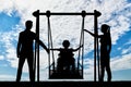 Silhouette of a happy child is a disabled person in a wheelchair on an adaptive swing Royalty Free Stock Photo