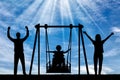 Silhouette of happy child is disabled in a wheelchair on an adaptive swing with mom and dad. have fun together Royalty Free Stock Photo