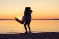 Silhouette of happy couple on beach at sunset, man taking the girl in his arms. Royalty Free Stock Photo