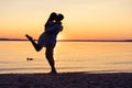 Silhouette of happy couple on beach at sunset, man taking the girl in his arms. Royalty Free Stock Photo