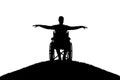 Silhouette of happy disabled man in wheelchair on top of hill