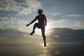 Silhouette of happy and excited woman jumping on the air above sea water at beautiful beach on sunset in freedom and excitement Royalty Free Stock Photo