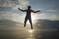 Silhouette of happy and excited woman jumping on the air above sea water at beautiful beach on sunset in freedom and excitement Royalty Free Stock Photo