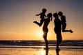 Silhouette of happy family who playing on the beach at the sunset time. Royalty Free Stock Photo