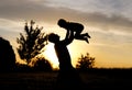 Silhouette of Happy Father Lifting Toddler Child in Air at Sunset