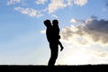 Silhouette of Happy Father Lovingly Hugging Little Child Outside at Sunset