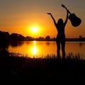 Silhouette of a happy girl with a guitar on a sunrise Royalty Free Stock Photo