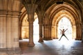 Silhouette of happy girl jumping high up in cloisters of Glasgow University Royalty Free Stock Photo