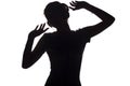 Silhouette of a happy girl listening to music in headphones, figure of young woman with hands up relaxing on a white isolated