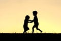 Silhouette of Happy Little Children Dancing at Sunset Royalty Free Stock Photo