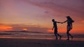 Silhouette of happy loving couple meet and play at the beach on sunset in ocean shore Royalty Free Stock Photo