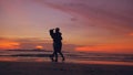 Silhouette of happy loving couple meet and play at the beach on sunset in ocean shore Royalty Free Stock Photo