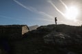 Silhouette of happy man standing on top of hill with sun back light and mountain la rhune in the back, basque country, france Royalty Free Stock Photo