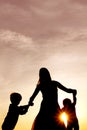 Silhouette of happy mother and little children dancing outside a Royalty Free Stock Photo