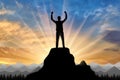 Silhouette of a happy mountaineer on top of a mountain.