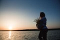 silhouette of a happy and proud pregnant woman by the river at sunset Royalty Free Stock Photo