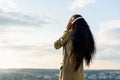 Silhouette of happy smiling young black african american woman with long hair listening to music. Blurred cityscape on Royalty Free Stock Photo