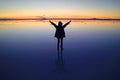 Silhouette of a happy Traveler rising arms with V Sign on the amazing mirror effect of Uyuni Salt Flats at sunset, Bolivia Royalty Free Stock Photo