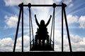 Silhouette of a happy woman is a disabled person in a wheelchair on an adaptive swing for disabled people