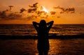 Silhouette of Happy woman standing with hands on head while sunset at sea,Freedom concept Royalty Free Stock Photo